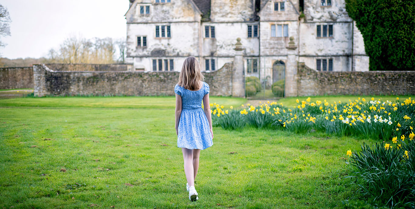 Girl Walking On Grass Towards A Building