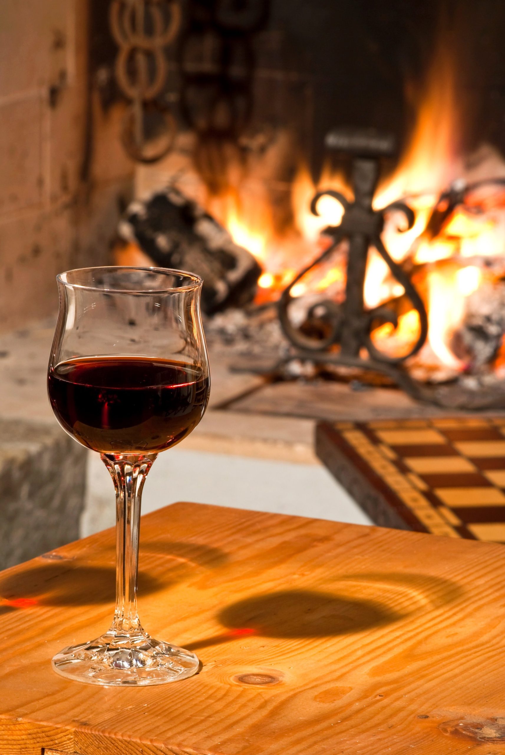 A Glass of red Wine On A Table Infront Of A Fire