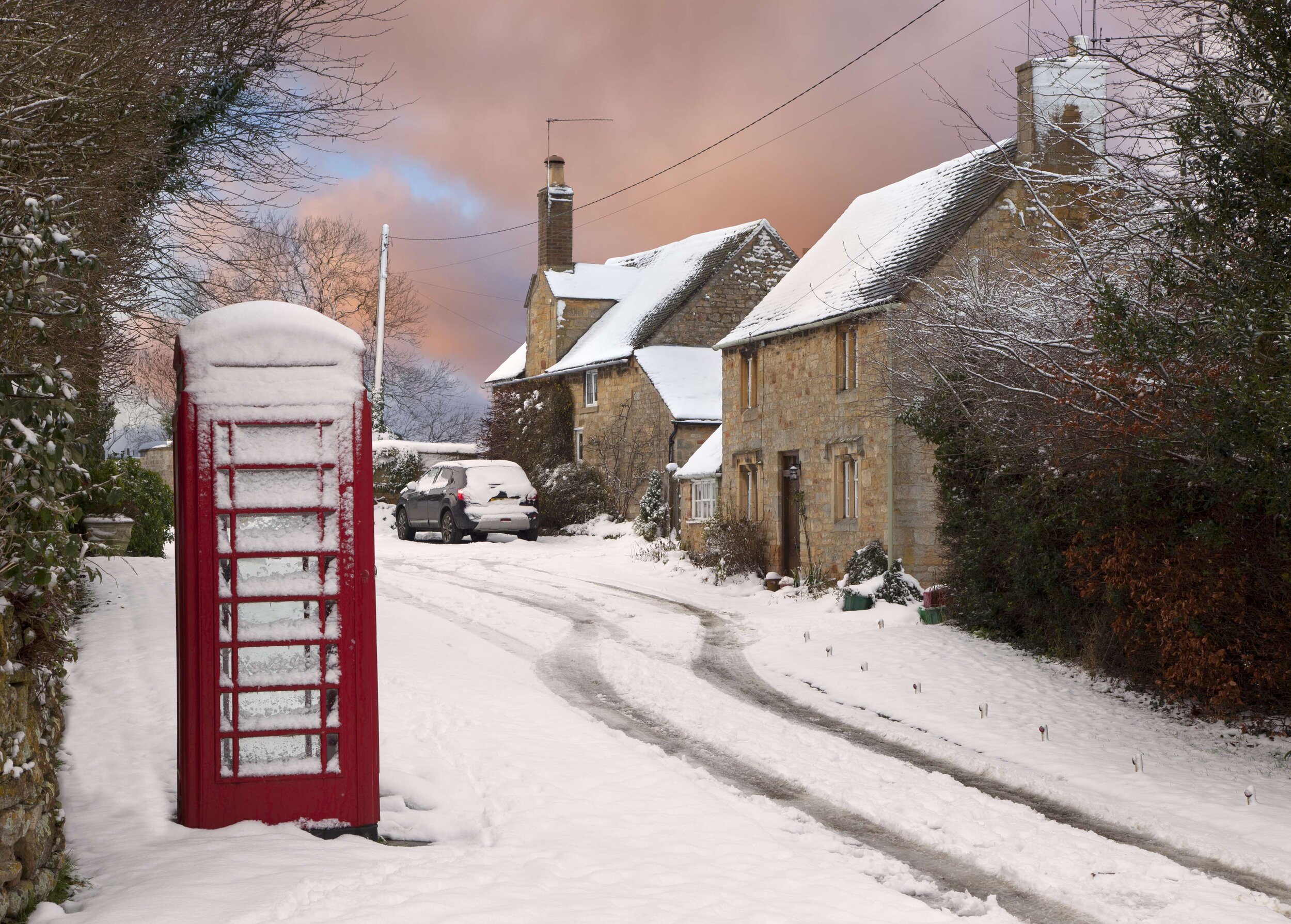 A Village Covered In Snow With A red Phone Box
